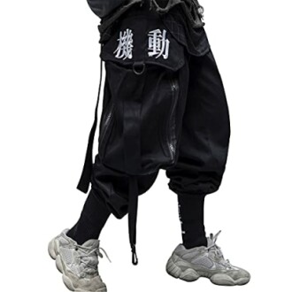 Person wearing black streetwear pants with white text and gray sneakers.