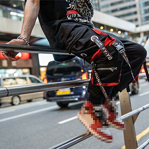 Person in streetwear sitting on railing in city