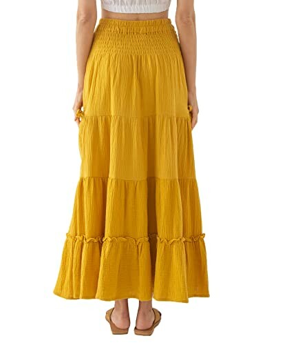 Back view of a woman wearing a yellow tiered maxi skirt.